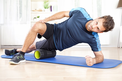 man using foam roller on leg