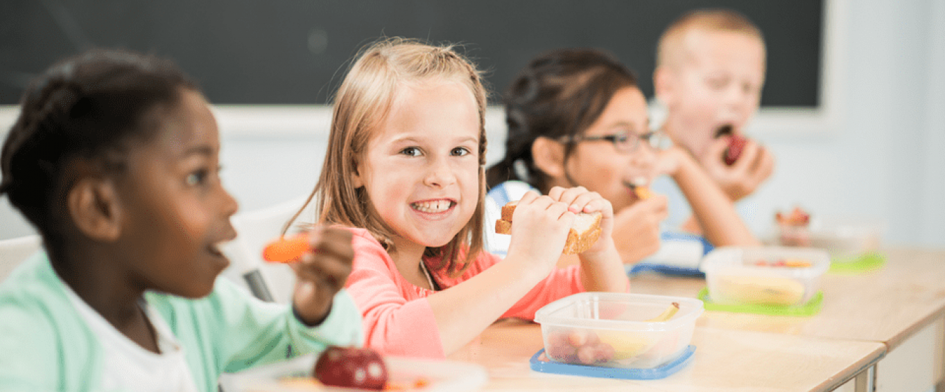 kids eating their packed lunch at a classroom desk kids eating their packed lunch at a classroom desk