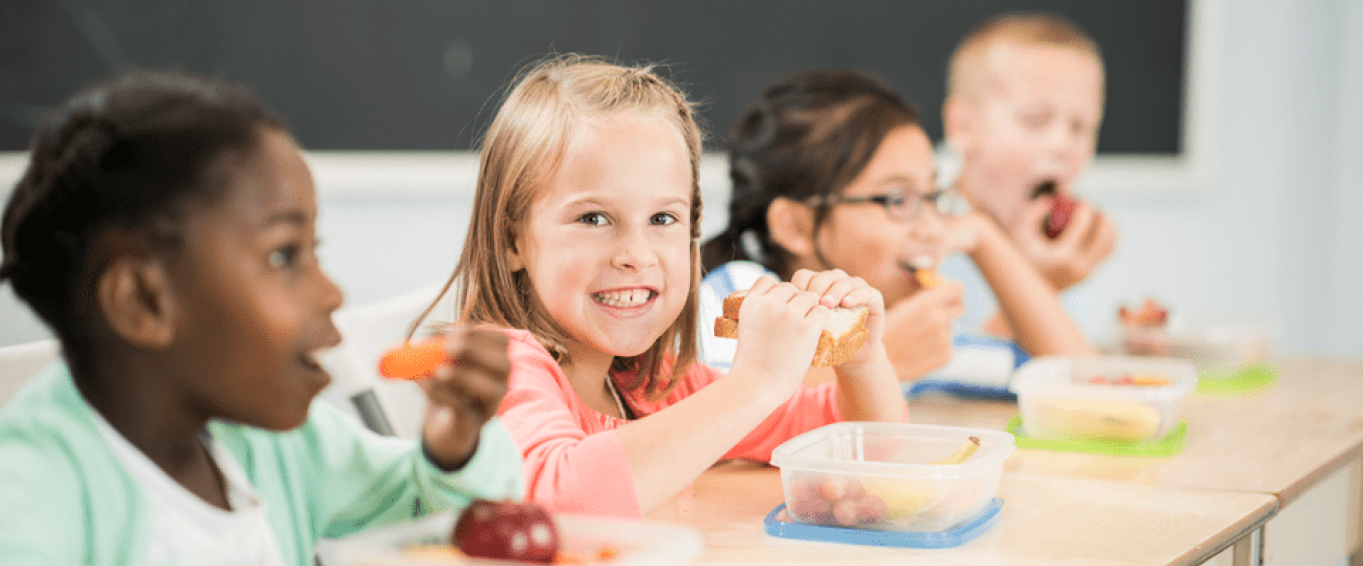 kids eating their packed lunch at a classroom desk