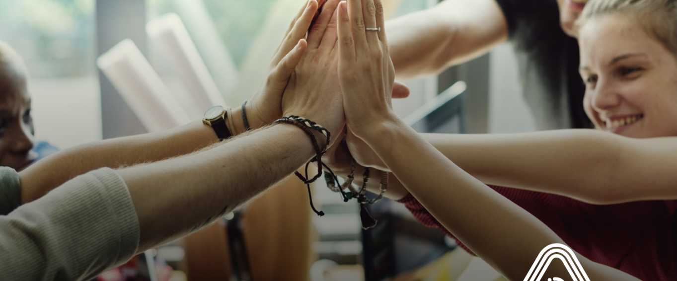 Group of people high fiving at desk Group of people high fiving at desk