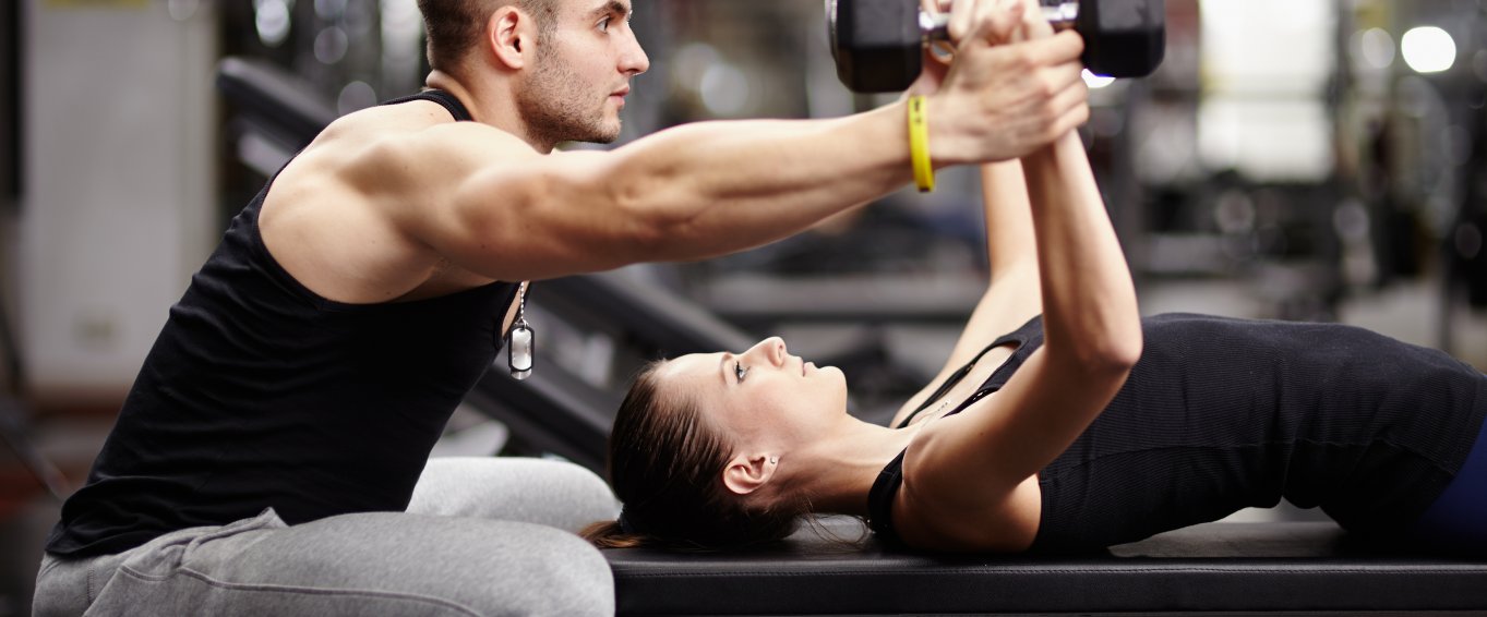 Personal Trainer Helping a Woman Lift Weights Personal Trainer Helping a Woman Lift Weights