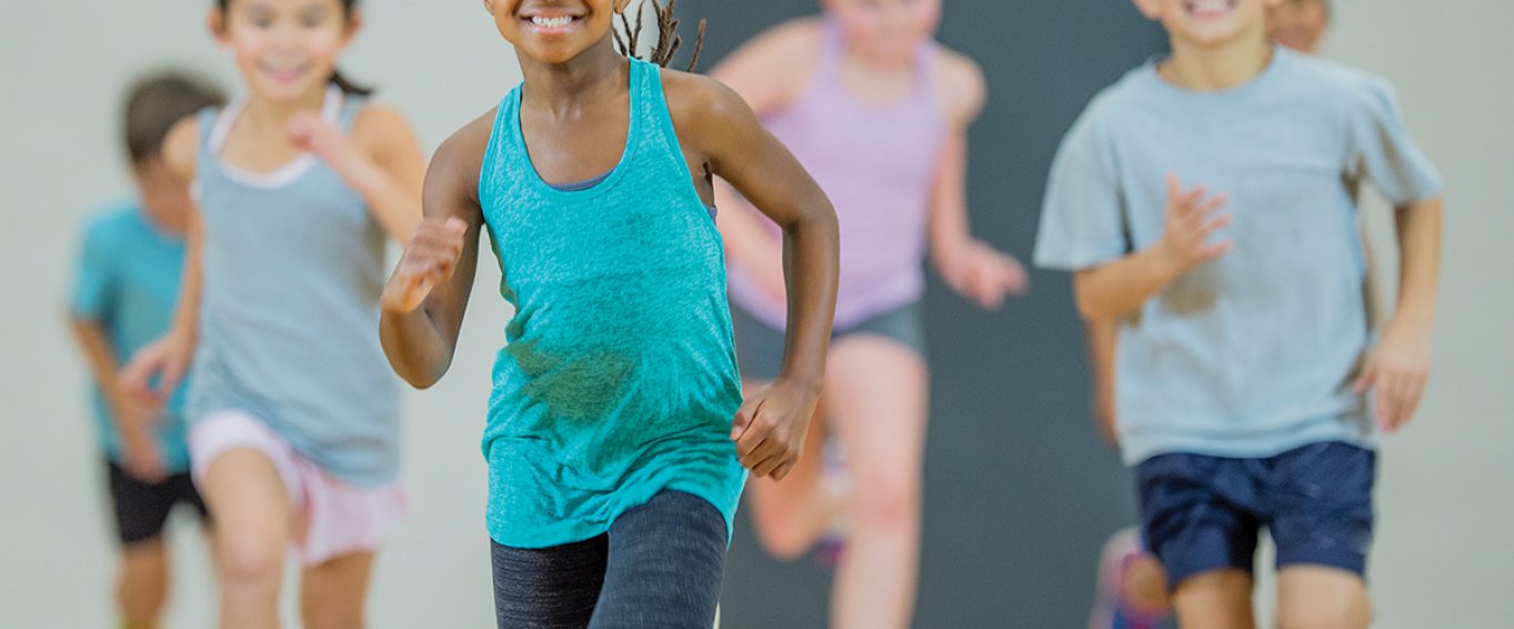Young Children Smiling and Jogging in Gym Class