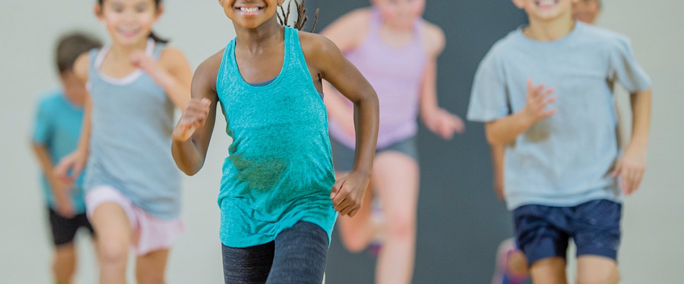 Young Children Smiling and Jogging in Gym Class Young Children Smiling and Jogging in Gym Class