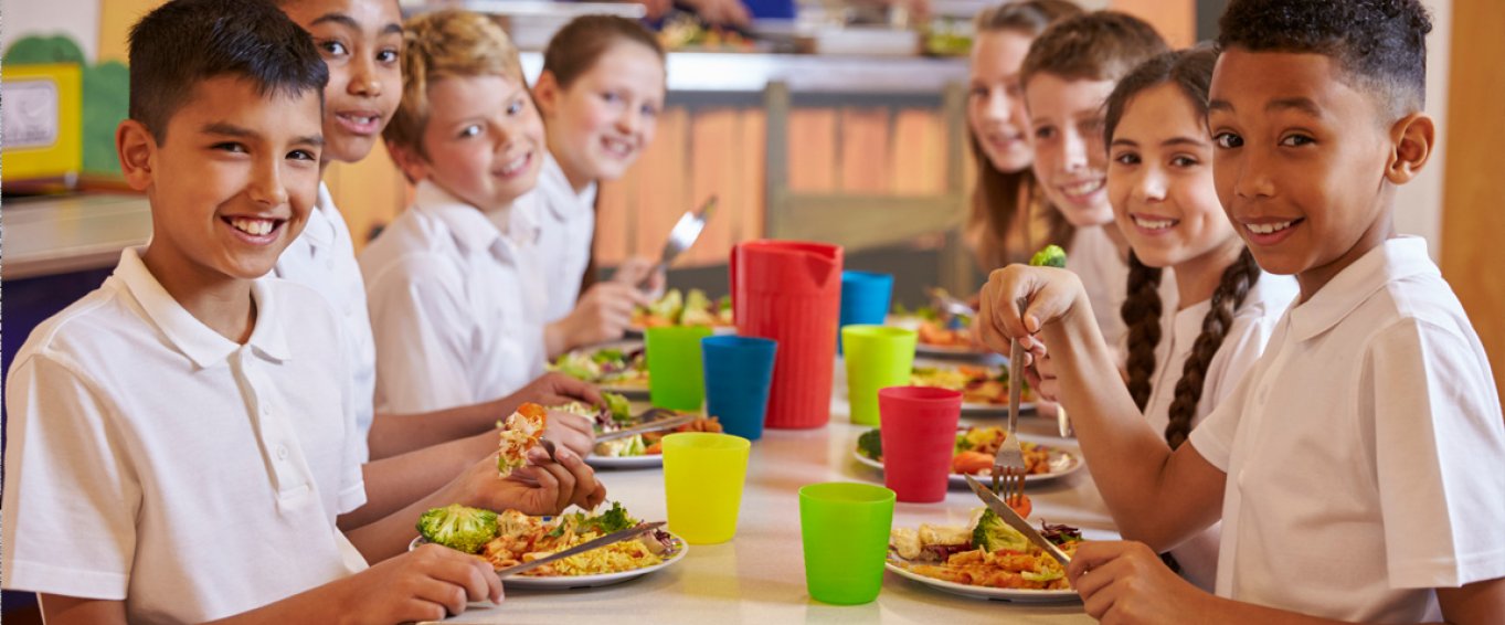 Eight Smiling School Children Eating School Lunch Together