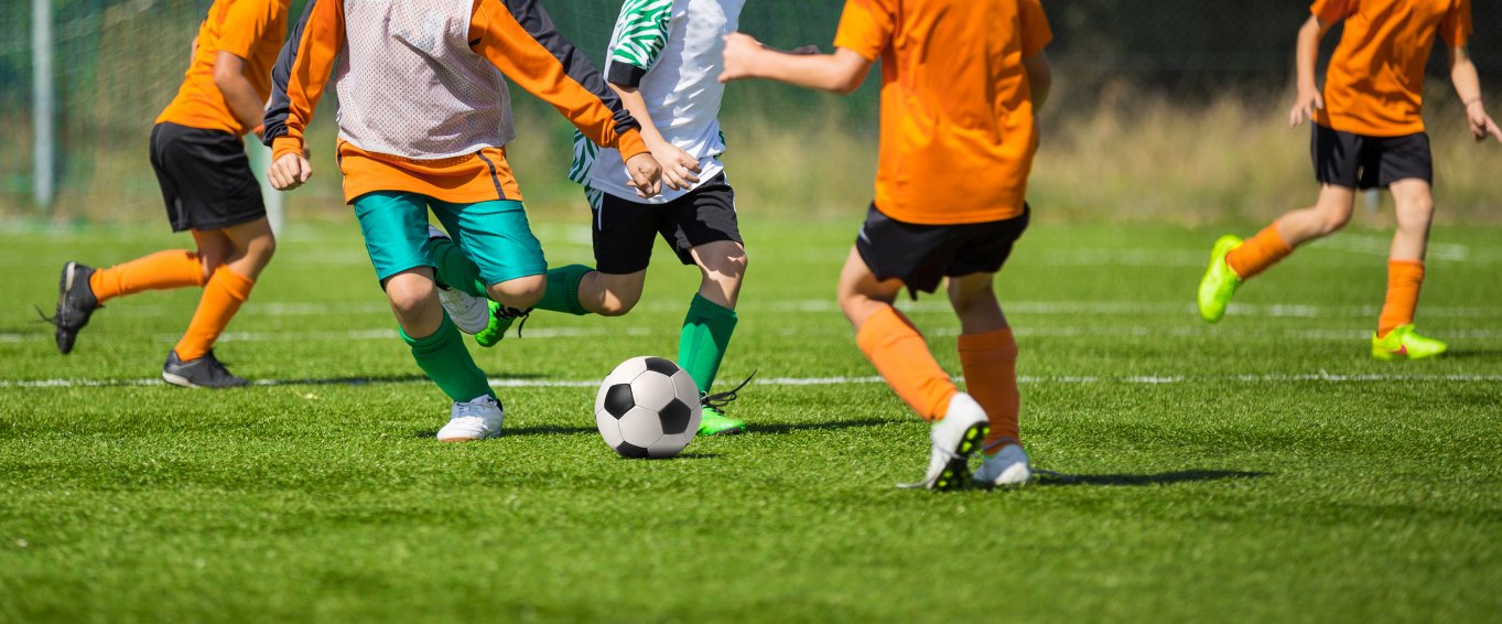 Five Boys in Orange Shirts Playing Football 