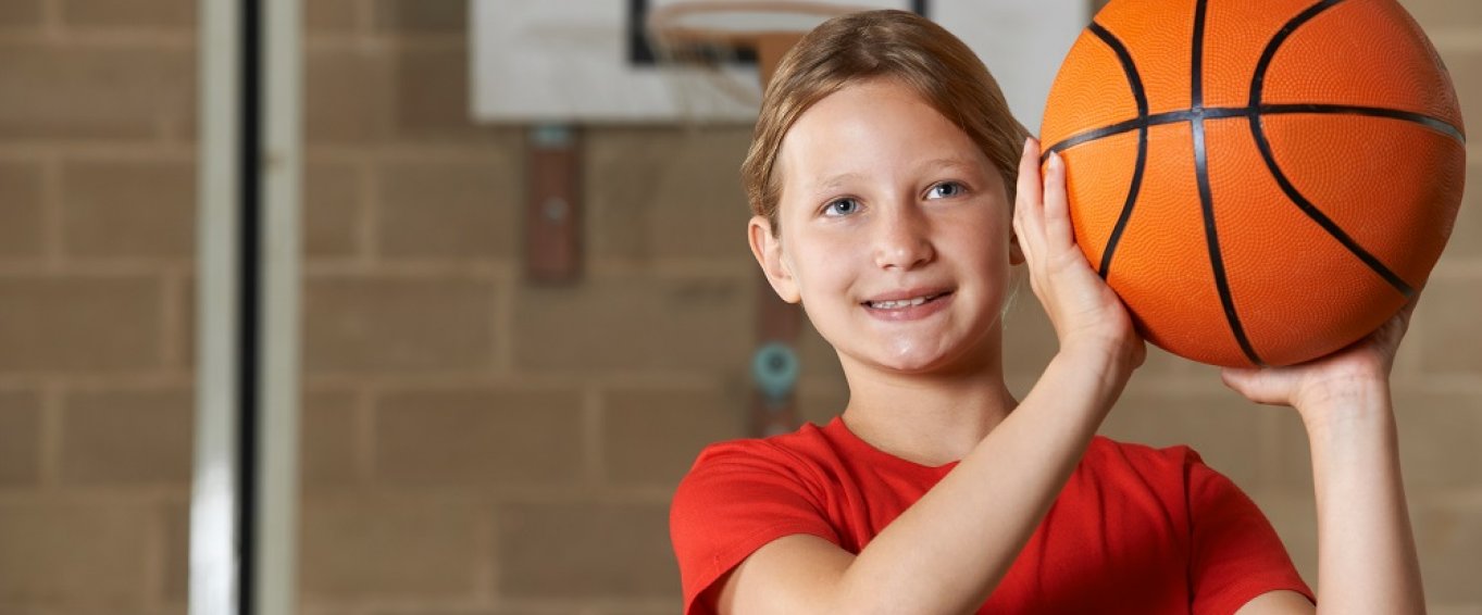 Young Girl Smiling and Holding a Basketball 