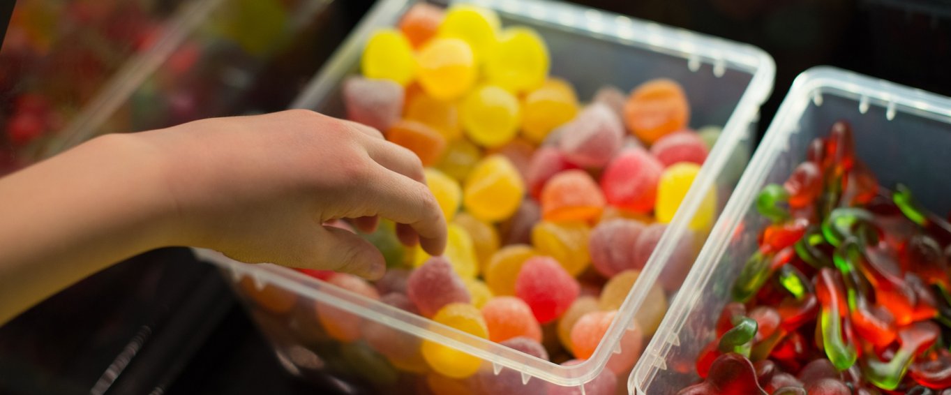 Child's Hand Dipping Into a Pick and Mix Box of Sweets Child's Hand Dipping Into a Pick and Mix Box of Sweets