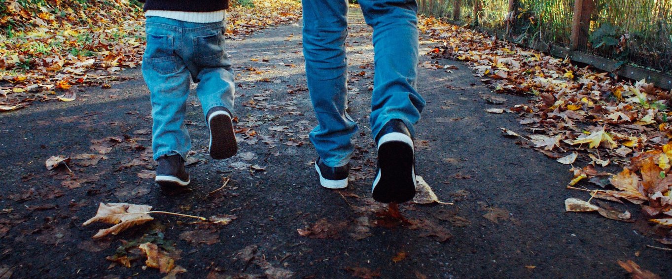 Dad Walking with His Son Through Autumn Leaves Dad walking with his son through Autumn leaves