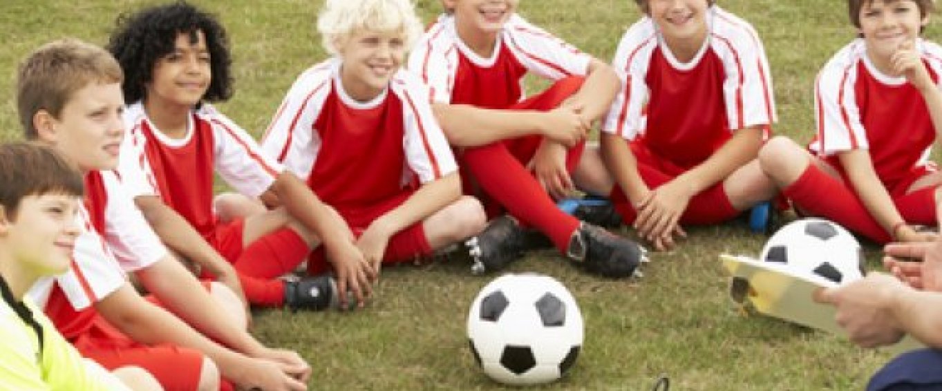 Kids football team sat around a football