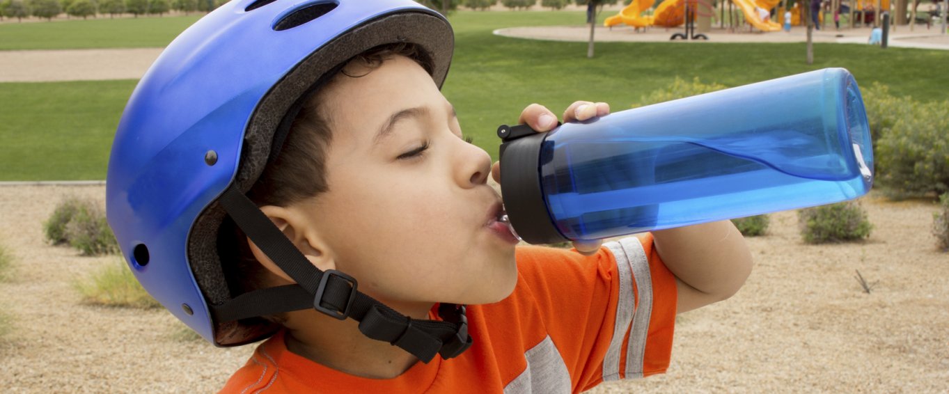 Young Boy in a Blue Bike Helmet Drinking from a Water Bottle