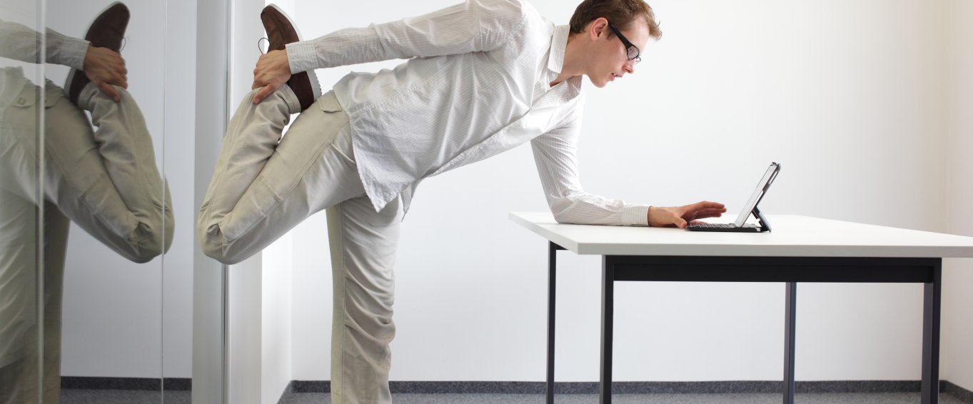 Man in white shirt stretching at desk