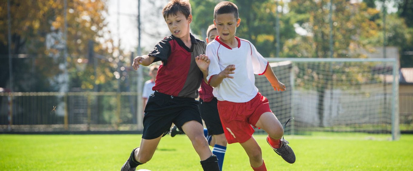 two boys playing football on grass