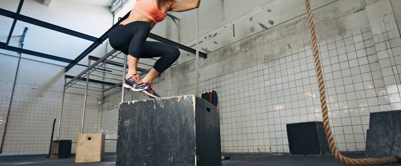 Woman jumping on box in gym Woman jumping on box in gym