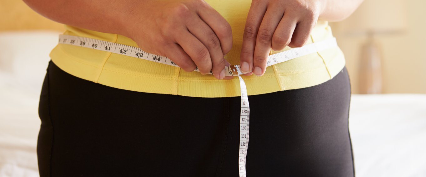 Woman in yellow top measuring waist 