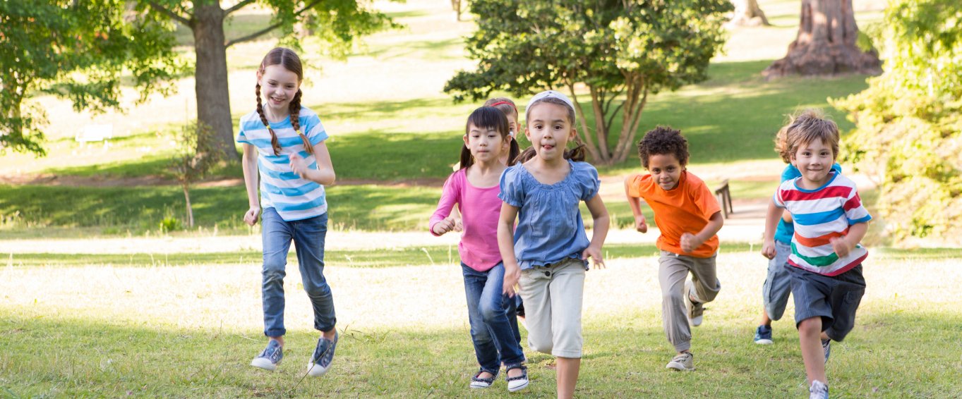 Children running up a grassy hill