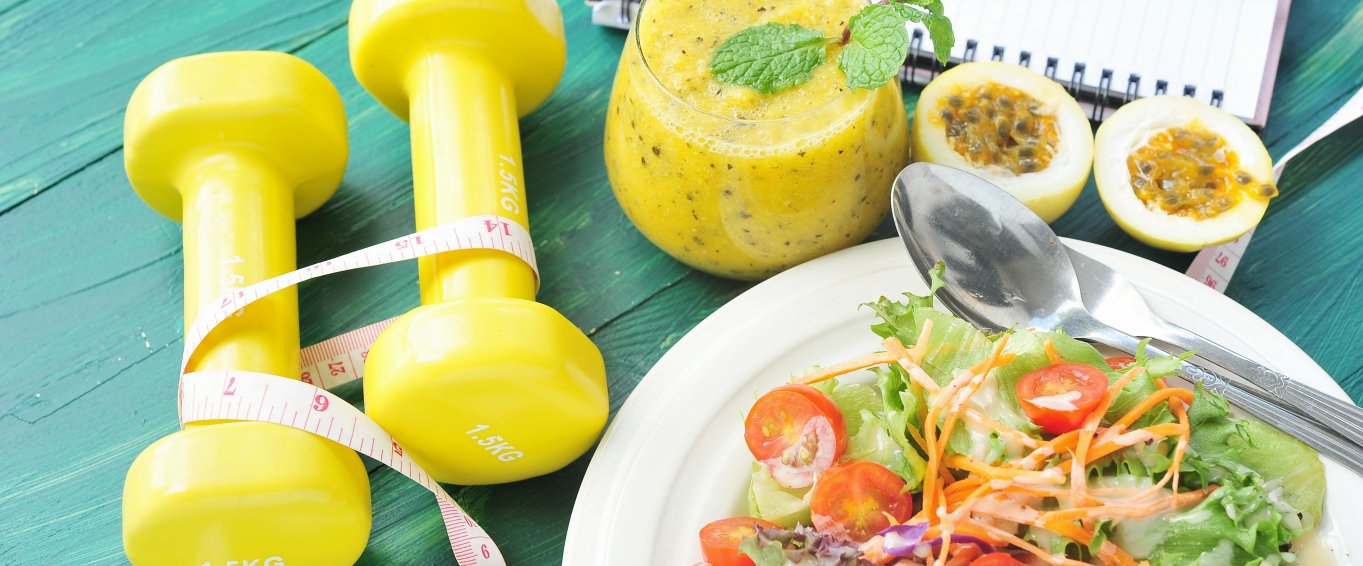 Healthy food and weights on a blue table