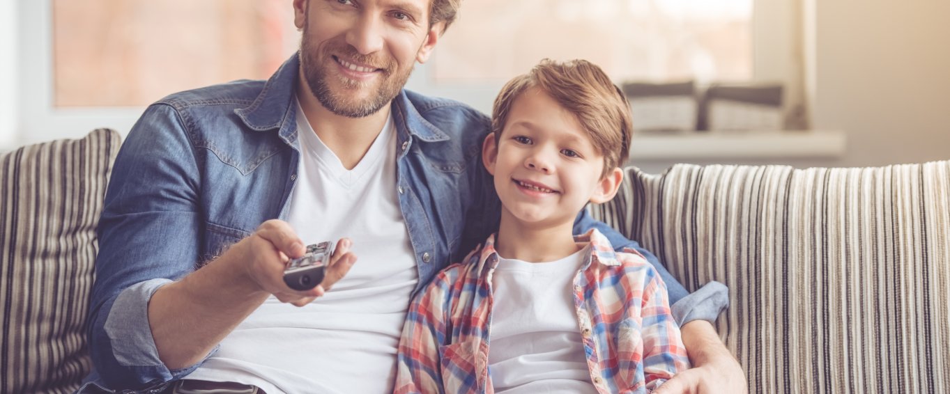 Man and child sat on sofa watching tv Man and child sat on sofa watching tv