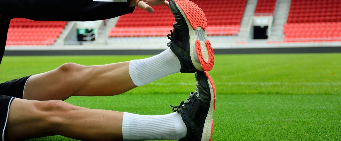 Footballer stretching out leg on football pitch Footballer stretching out leg on football pitch