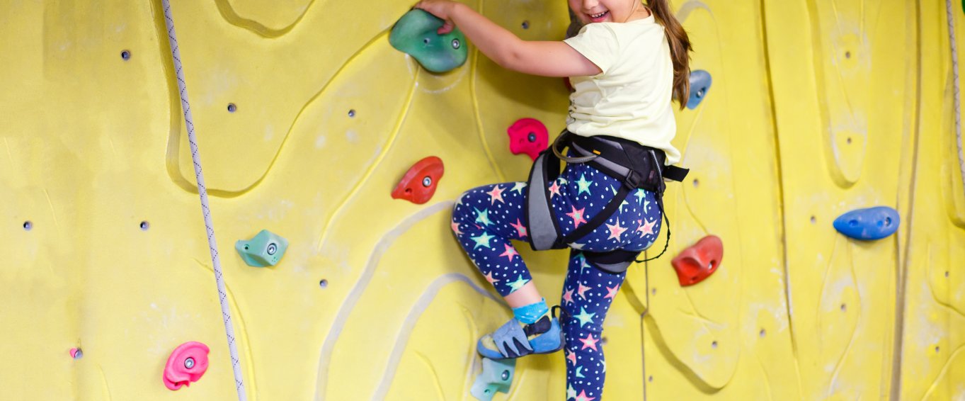 Young girl indoor rock climbing smiling