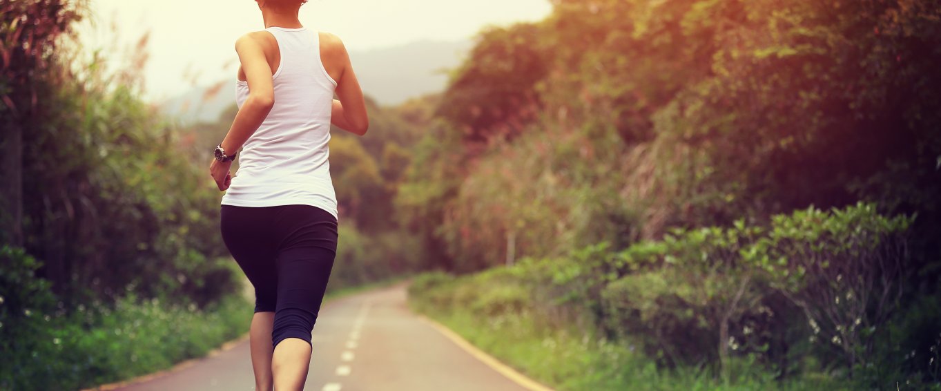 woman jogging down wooded road 