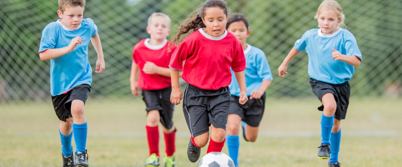 5 Children in Footie Kits Chasing a Football