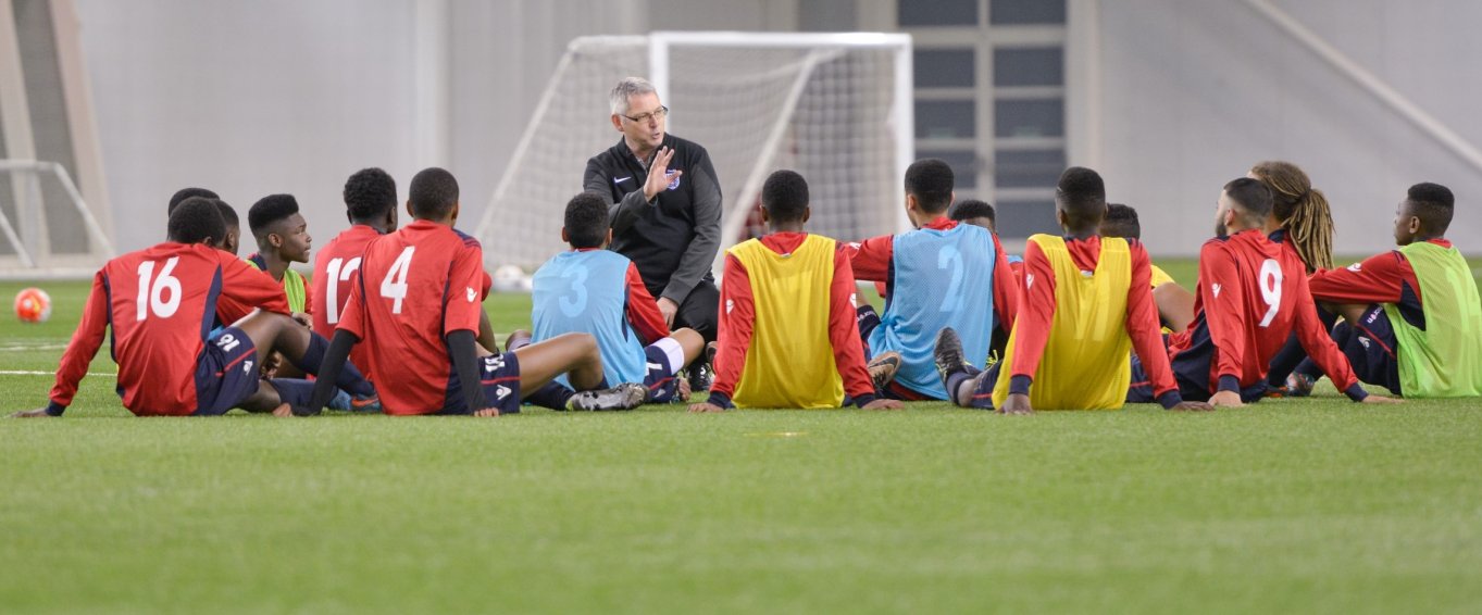 Coach talking to youth football players in front of a goal