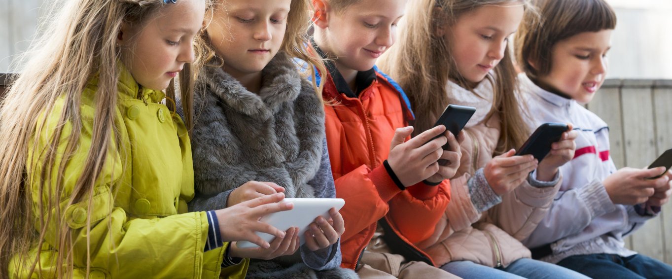 Young Children Staring At Their Mobile Phones 