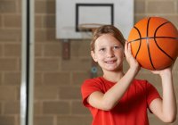 Young Girl Smiling and Holding a Basketball 