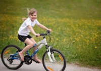 Young Girl Riding a Bicycle & Smiling