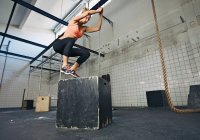 Woman jumping on box in gym