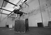 Woman jumping on box in gym