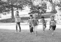 Children running up a grassy hill