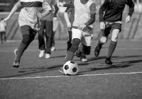 Young boys playing football on pitch Amaven 