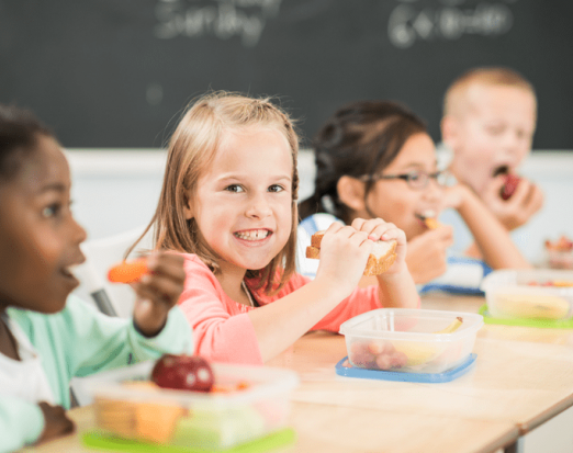 kids eating their packed lunch at a classroom desk