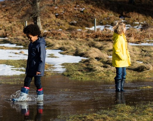 Two Children in Winter Clothes Splashing In a Stream