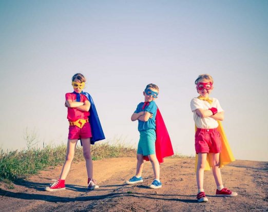 Three Children Posing in Superhero Capes and Masks