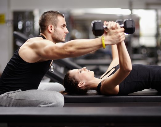 Personal Trainer Helping a Woman Lift Weights 