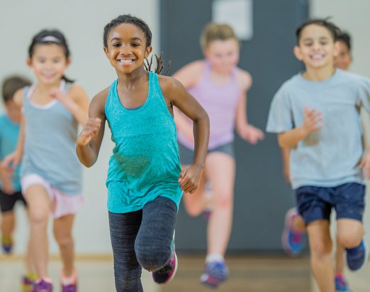 Young Children Smiling and Jogging in Gym Class