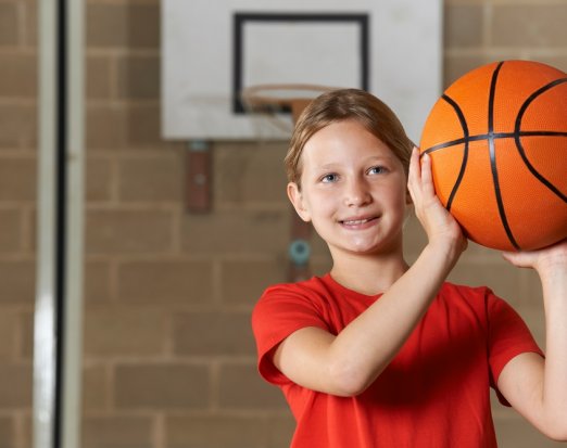 Young Girl Smiling and Holding a Basketball 