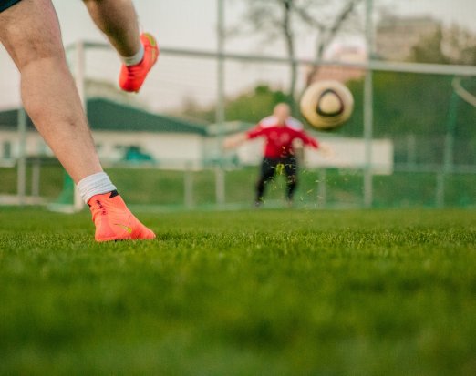 Boy Kicking Football at a Goalie