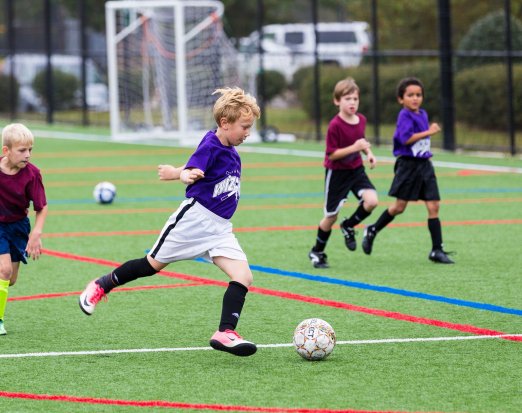 Four Young Boys Playing Football