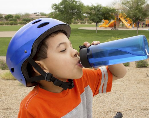 Young Boy in a Blue Bike Helmet Drinking from a Water Bottle