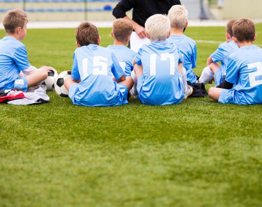 Boys football team sat listening to coach