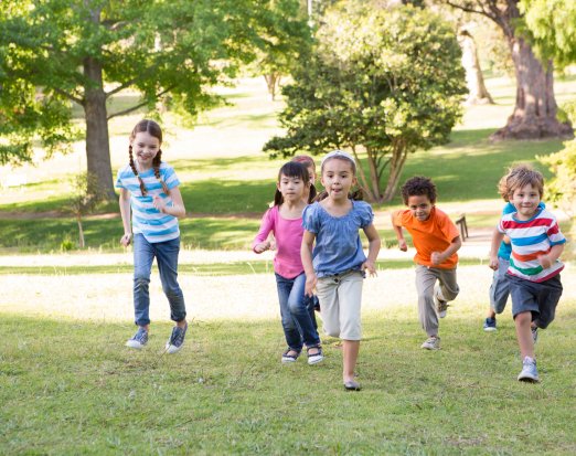 Children running up a grassy hill