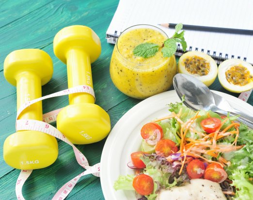 Healthy food and weights on a blue table