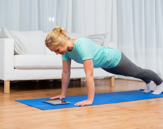 Woman doing press up while looking at tablet