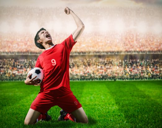 Male footballer celebrating goal infront of crowd
