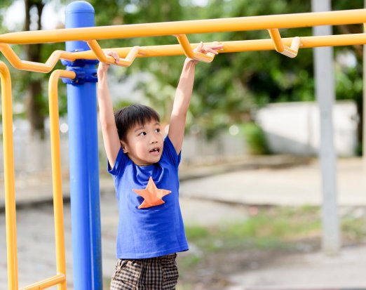 Boy doing monkeybars climbing frame