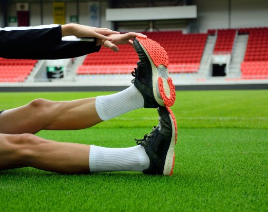 Footballer stretching out leg on football pitch