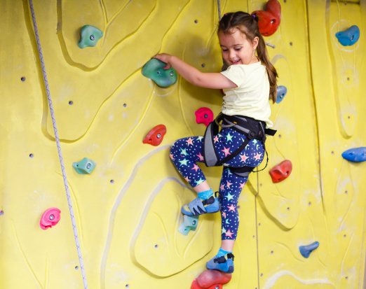 Young girl indoor rock climbing smiling